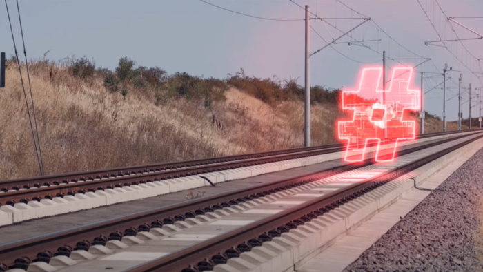 Zweigleisige Zugstrecke mit Oberleitungen in einer bepflanzten Landschaft. Auf dem rechten Gleis fliegt ein rot transparentes Hashtag.. Zweigleisige Zugstrecke mit Oberleitungen in einer bepflanzten Landschaft. Auf dem rechten Gleis fliegt ein rot transparentes Hashtag..