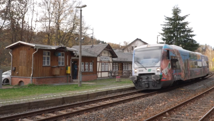 Ein Zug hält an einem kleinen Bahnhof.