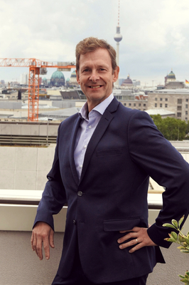 Ein Mann steht auf einer Dachterrasse. Im Hintergrund ist ein Kran zu sehen.
